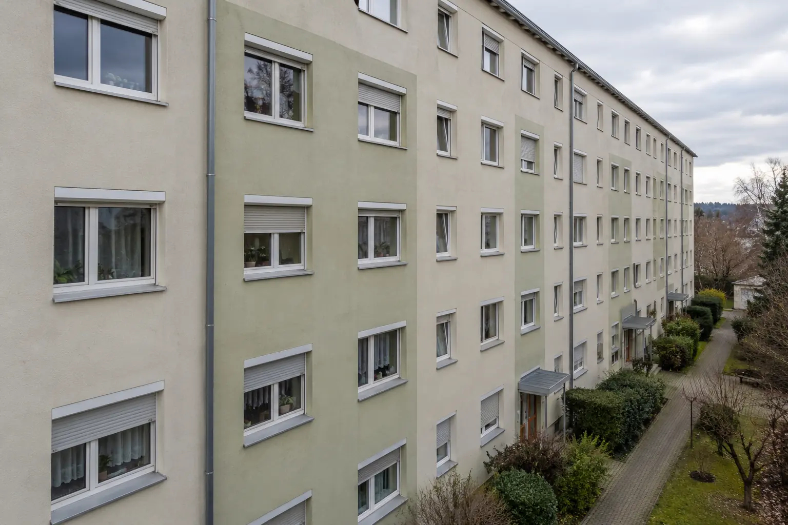 Fassade eines Wohnblocks mit Fensterreihen und Rollladenkästen